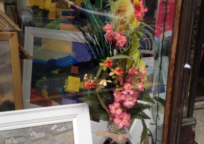 A floral display with small bird in the window of an art gallery