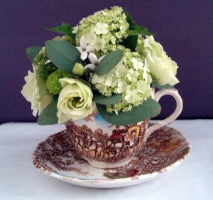 Green flowers in brown cup and saucer by Shrinking Violet